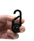 Hand holding Two Pack Outdoor Hiking Compass With Carabiner Keychain Go-To Pocket Navigation Tool in black.
