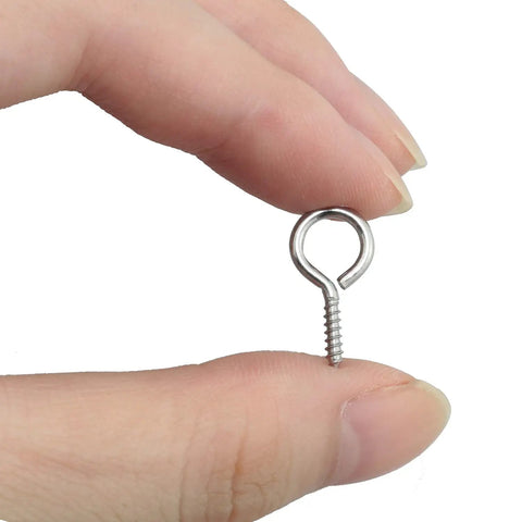 Hand holding a Handy 100 Pack 0.67 Inch Stainless Steel Eye Screws Heavy Duty Eye Bolts for Hanging Photos and Decor DIY Jewelry Making.