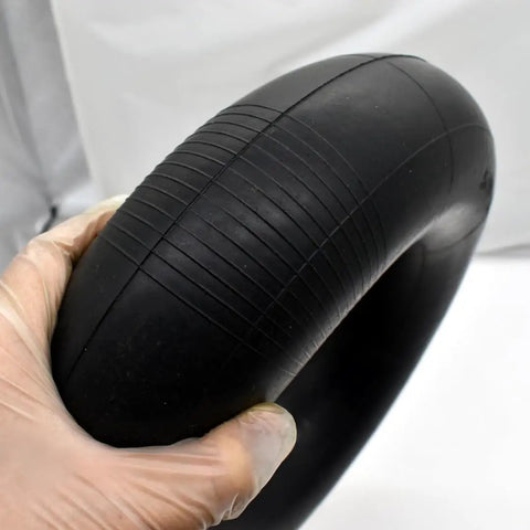 Close-up of Heavy Duty 5.00-6 Inner Tube With TR87 Bent Valve Stem For 13X5.00-6 And 12X5.00-6 Tires, held in gloved hand.