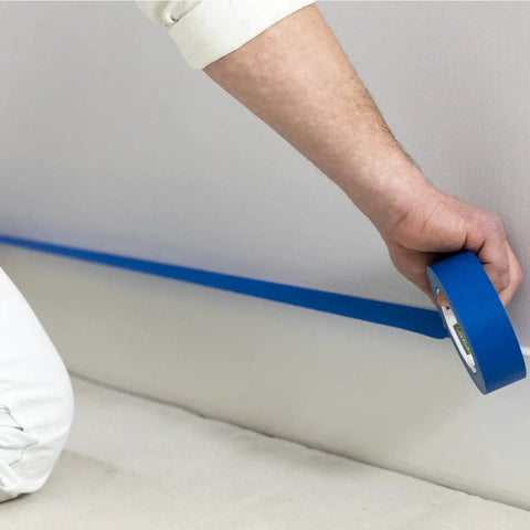 Blue Painters Tape With PaintBlock For Sharp Lines, 2 Inch Wide Painter Tape, used by person on wall, medium adhesion, clean removal up to 14 days