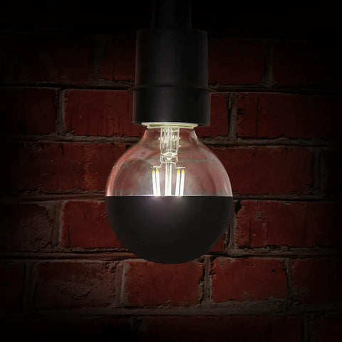G25 DM Black Mirror Dome Filament LED Light Bulb 40W Equivalent, glowing against a red brick wall