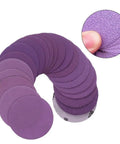 Check Out These Badass 3 Inch Sanding Discs With 320 Grit Aluminum Oxide Abrasive For Wet Dry Sanding And Waterproof Latex Backing Plus Hook System For Long Life On All Your Projects - Assorted purple sanding discs arranged in a spiral.