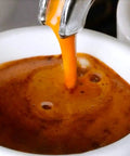 Close-up of espresso being extracted into a cup from a commercial espresso machine spout.