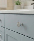Polished Chrome Round Cabinet Knobs 10 Pack With Intricate Filigree Pattern And Decorative Cutouts For Cabinets And Drawers 1.4 Inch Diameter And Easy Grip on a blue cabinet