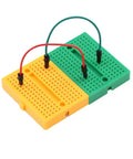 Interlocked green and yellow mini solderable breadboards for Arduino, with wires; part of Seven Pack Mini Solderable Breadboards With 170 Tie Points Each For Tiny Prototyping Arduino Shield Projects Solderless Breadboard Kit For Quick Circuits And Neat Layouts.