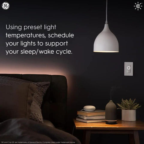 Bedroom with Cync Smart Home Starter Kit with Color Changing LED Bulb, wireless dimmer switch, bedside table, lamp, and decor.