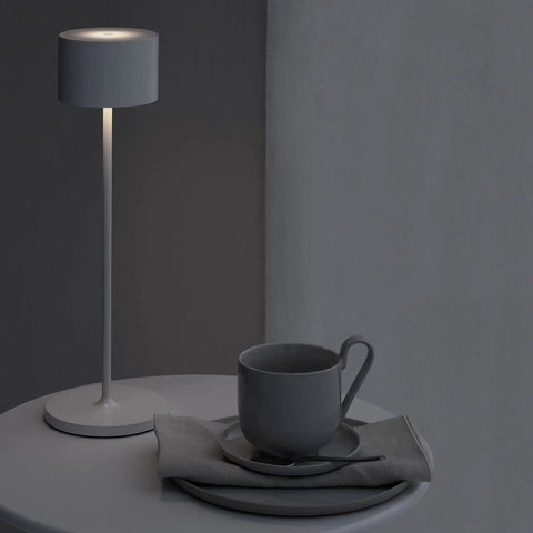 Super Sleek Portable LED Lamp In Warm Gray, Farol Mobile Light next to gray mug on a table, perfect for home or desk, battery powered