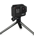 3 In 1 Do It All Action Camera Grip Arm And Tripod For All In One Stability with a camera on tripod mode on a flat surface.