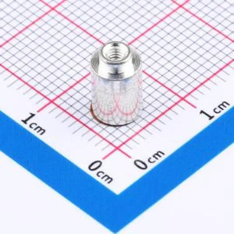 Close-up of a Copper Tinned M2x7 SMD Round Nut Column on a grid, part of 10 Pack Heavy Duty SMD Round Nut Columns Surface Mount PCB Connectors.
