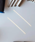 Get A 40pc Kit Of High Grade White Pp Plastic Welding Rods Stricks For Quick Car Bumper Repair And Auto Body Fixes To Fix Rips And Cracks Like A Boss - Two white plastic welding rods on a gray surface.