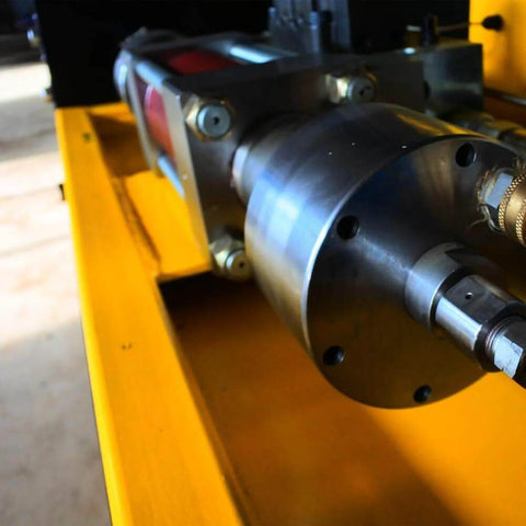 Close-up of waterjet intensifier pump assembly with metallic housing and drive shaft mounted on a yellow frame
