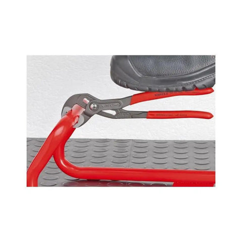 Cobra Water Pump Pliers 10 Inch With Self Locking Grip holding red pipe, side view with boot stepping for pressure application