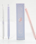 Gel Pens Set Cute Stationery Trio With 0.5mm Fine Point Quick Dry Ink For Journaling And Aesthetic Office Vibes Two Black And One Coral Ink Smooth Write No Skip No Bleed next to decorative box.