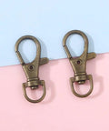60 Pack Bronze Swivel Clasps Featuring Lanyard Snap Hooks With Key Rings Plus Lobster Claw Clips For Jewelry Making And Diy Crafts Hella Durable Zinc Alloy Construction Smooth 360 Spin Action Badass Quality That Lasts - Close up of two bronze swivel clasps