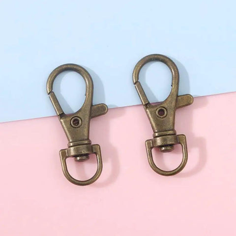 60 Pack Bronze Swivel Clasps Featuring Lanyard Snap Hooks With Key Rings Plus Lobster Claw Clips For Jewelry Making And Diy Crafts Hella Durable Zinc Alloy Construction Smooth 360 Spin Action Badass Quality That Lasts - Close up of two bronze swivel clasps