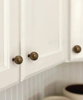 10 Pack Antique Brass Cabinet Knobs 0.9 Inch Round Solid Zinc Alloy Vintage Dresser Drawer Pulls on white cupboard
