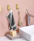 Foldable Wall Mounted Coat Hook Built With Heavy Duty Steel No Sweat Install, holding a towel and brush in a modern bathroom.