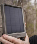 Person holding Reveal 12V External Solar Panel With Integrated Rechargeable Battery For Cellular Trail Cameras outdoors