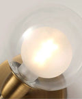 Rock This Mini Two Light Gold Bathroom Vanity Wall Sconce With Clear Glass Shades close-up of lit bulb in clear glass shade