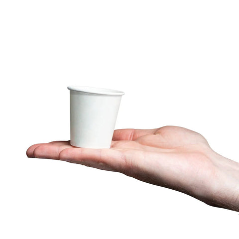 A hand holding a 3 Oz White Paper Cup from the Set Of 600 For Espresso Tea Samples And Mouthwash Small Disposable Cups for drinks.