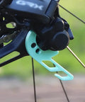 Close-up of black bike with turquoise Bike Chain Keeper And Rear Derailleur Stabilizer Clip for Shimano 12 Speed Electronic Shifting.