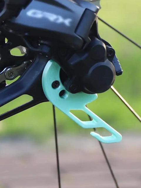 Close-up of black bike with turquoise Bike Chain Keeper And Rear Derailleur Stabilizer Clip for Shimano 12 Speed Electronic Shifting.