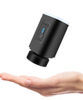 Portable cordless black vacuum pump with blue indicator for vacuum storage bags, shown above a palm for scale