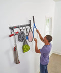 FastTrack Garage Hook Kit And Tool Organizer With All In One Rail, holding sports gear and tools on a white wall.
