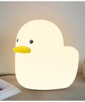 Duck Shaped Silicone Night Light For Nursery exposed on table with warm white LED glow, BPA free lamp for sleep aid.