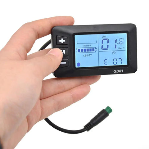 Hand holding Weatherproof 5 Pin LCD Display for Electric Bikes showing speed and assist levels, Waterproof Bike Dashboard for 22.2mm Handlebars, Easy Install GD01 Style Indicator, DIY Modification Accessory for Cyclists