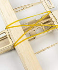 Close-up of laser-cut balsa wood frame from Beginner Friendly Balsa Wood RC Airplane Kit With 580mm Wingspan Laser Cut Unassembled Flying Model For Adults R03 Stick06 Design DIY RC Aircraft Kit Includes Motor ESC Servos And Covering For Easy Build, showing rubber bands and intricate details.