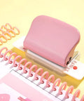 Pink Six Hole Paper Punch For A4 A5 Notebooks with 6mm holes, shown with spiral binders and paper on yellow background.