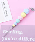 Premium Color Coded Scriber Needle For Sugar Craft And Cake Decorating Icing Pin with colorful beads and steel needle on pink background.