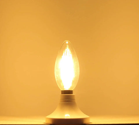 LED Filament E14 Candle Light Bulb 2700K Warm White, 400 Lumens glowing on a base, clear glass torpedo top, illuminated in warm light