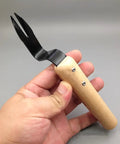 Person holding Stainless Steel Hand Weeder Tool With Wood Handle Garden Weed Puller for Manual Weeding and Weed Removal