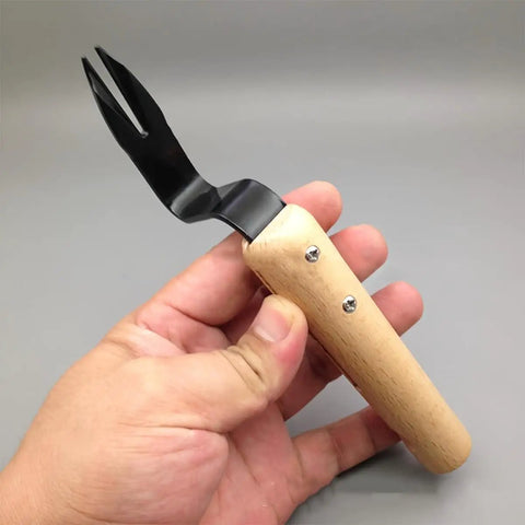 Person holding Stainless Steel Hand Weeder Tool With Wood Handle Garden Weed Puller for Manual Weeding and Weed Removal