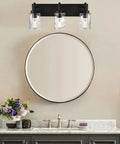 Three Light Modern Vanity Wall Sconce In Black With Hammered Glass Shades For Dope Bathroom Lighting Mirror Cabinets Powder Room Dressing Table Farmhouse Vibe above round mirror in a bathroom.