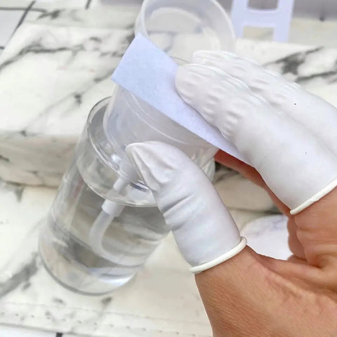 Hands wearing Latex Finger Cots 400 Count Small Disposable Fingertip Gloves holding a cotton pad near a bottle