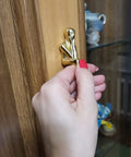 Close-up of a hand installing Brass Thinker Shape Cabinet Pulls Gold Finish Artful Abstract Drawer Handles for Cabinets and Furniture.