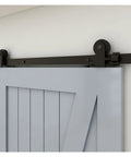 Close-up of Badass Heavy Duty Sliding Barn Door Hardware Kit With Fourteen Foot Track And Industrial Carriage Rollers mounted on a gray wooden door.