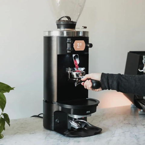 Pro Automatic Espresso Tamper in use with Mahlkonig E80 Grinder, showcasing durable matte black shell, precise tamping process.