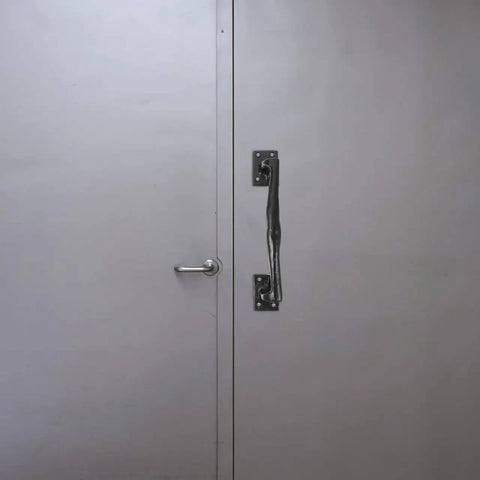 Old School Vintage Barn Door Handle for Sliding Doors and Gates, rustic metal gate pull on grey door, side view.