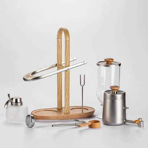 Top Shelf Belgian Siphon Coffee Maker With Clear Glass Chamber And Sleek Silver Base For No Fuss Morning Brews Delivering Legit Rich Flavor That Truly Is A Game Changer components on display, including glass, steel, and wood elements.