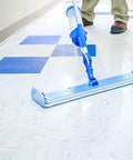 Person cleaning a vinyl floor with a blue mop using Badass Professional Floor Sealant With Tough Stain Guard For Vinyl Vct Concrete.