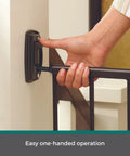 Hand demonstrating easy one-handed operation of Bulletproof Hardware Mounted Walk Thru Pet Gate 31 Inches Tall Fits 28 To 48 Inch Doorways Displays A Slick Matte Bronze Finish.
