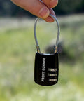 Small Stainless Steel Combination Cable Lock For Overland Truck Racks held in hand outdoors with a focus on resettable tumblers.