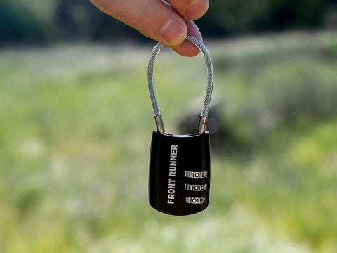 Small Stainless Steel Combination Cable Lock For Overland Truck Racks held in hand outdoors with a focus on resettable tumblers.