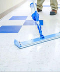 Person using a floor mop to apply Top Tier High Traffic Floor Polish In A Five Gallon Pail on tile floor.
