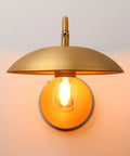 Dope Industrial Swing Arm Wall Sconce In Brass Finish Adjustable Hardwired Wall Lamp With Metal Base Retro Indoor Lighting Fixture For Hallway Bedroom Living Room Dining Area And Cafe Decor showing lit bulb beneath brass UFO-shaped shade and round metal base.
