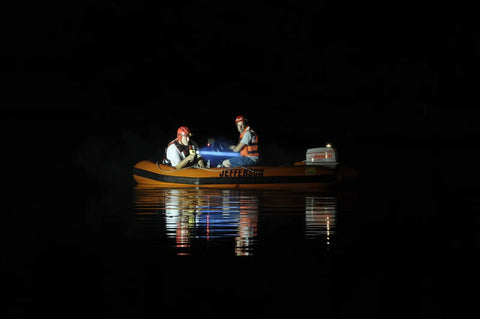 Two rescuers in a boat using the Waypoint Beefy 500 Lumen Handheld LED Spotlight For Outdoor Marine And Emergency Use With 100,000 Candela Peak Beam